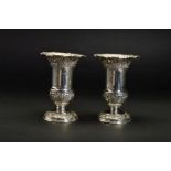 A PAIR OF LATE VICTORIAN SILVER VASES, of urn form, crimped rims above repousse wrythen and