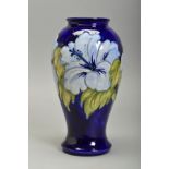 A MOORCROFT HIBISCUS DESIGN VASE, of baluster form, pale blue flowers on a dark blue ground,