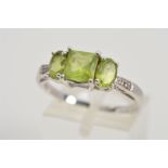 A 9CT WHITE GOLD PERIDOT RING, designed as a central square peridot flanked by oval peridots with
