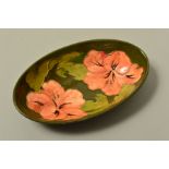AN OVAL MOORCROFT POTTERY BOWL, 'Hibiscus' pattern on green ground, impressed marks to base and an