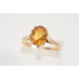 A 9CT GOLD CITRINE RING, designed as an oval citrine in a claw setting to the tapered shoulders
