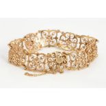 A 9CT GOLD PANEL BRACELET, the shaped openwork scrolling design panels to the push piece clasp, with