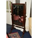 A VICTORIAN MAHOGANY FRAMED CHEVAL MIRROR, the rectangular mirror on reeded arms, linked by a turned