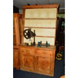 A DISTRESSED VICTORIAN PINE KITCHEN DRESSER, the top with a painted backboard and triple plate