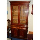 A VICTORIAN FLAME MAHOGANY GLAZED TWO DOOR BOOKCASE, with a single drawer and double cupboard doors,