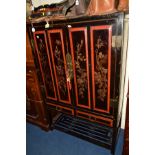 A 20TH CENTURY ORIENTAL TWO DOOR CABINET, black ground with red panelled border, the doors revealing