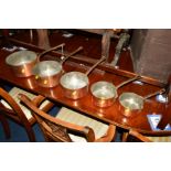 A SET OF FIVE COPPER GRADUATRING PANS with an iron hooped handles and a pine wall rack (6)