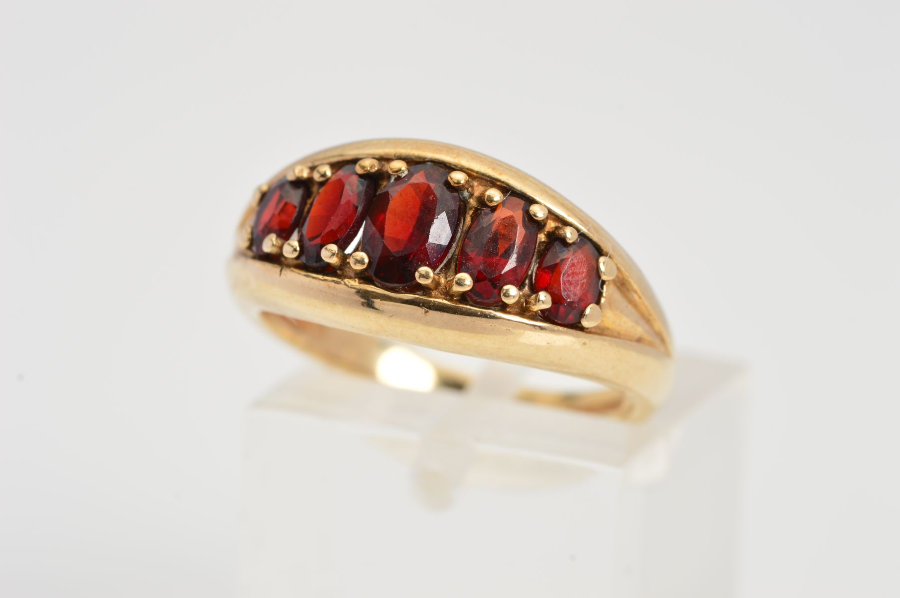 A 9CT GOLD GARNET RING, designed as five oval graduated garnets secured with four claw settings