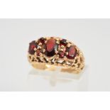 A 9CT GOLD GARNET RING, designed as oval and circular garnets within an open textured surround,