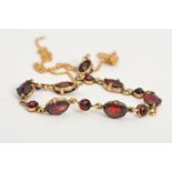 A GARNET NECKLACE, designed as seven oval claw set garnets interspaced by circular garnets to the
