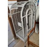 A GREY METAL FRAMED ARCHED BIRD CAGE, on casters, height 162cm x width 66cm x depth 57cm
