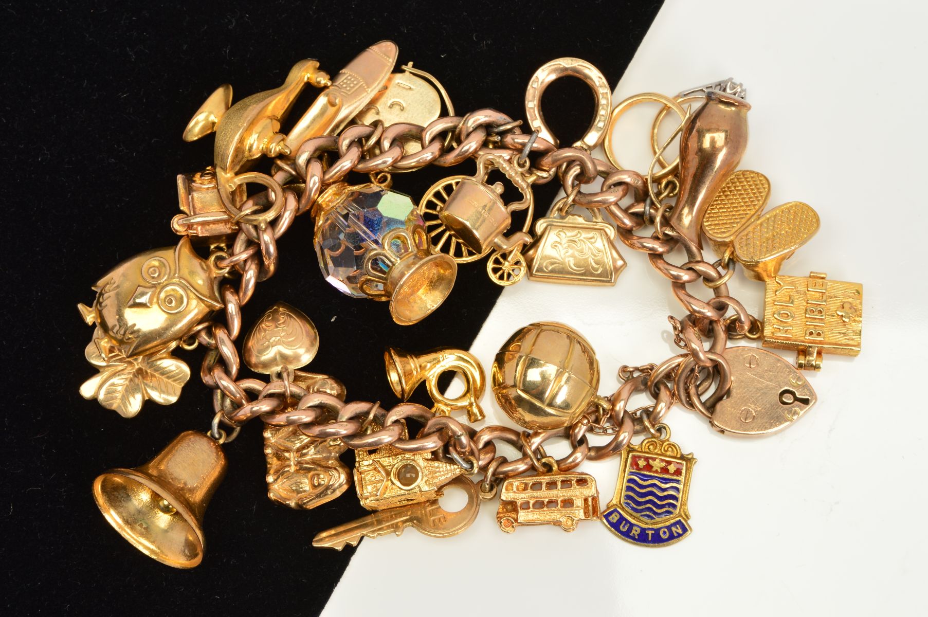 A CHARM BRACELET, the curb link bracelet suspending twenty four charms to include a Stanhope
