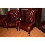 A PAIR OF REPRODUCTION WING BACK AND BUTTON BACK ARMCHAIRS IN OX BLOOD RED LEATHER, on cabriole legs