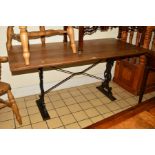 A RECTANGULAR OAK DINING TABLE ON A CAST IRON BASE, the ends with foliate scrolls and gilt masks,