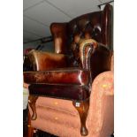 A BROWN LEATHER BUTTON BACK WING BACK ARMCHAIR (sd)