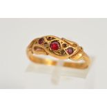 AN EDWARDIAN 18CT GOLD GEM RING, designed as a scrolling central panel set with three graduated
