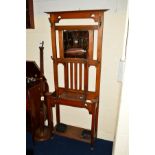 AN ART NOUVEAU OAK HALL STAND, with a central bevelled edge mirror, four coat hooks, hinged