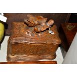 A BLACK FOREST TEA CADDY, in need of restoration, having carved fighting birds to the cover, width
