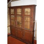 AN EDWARDIAN STAINED PINE BOOKCASE, with three glazed cupboard doors over three panelled doors