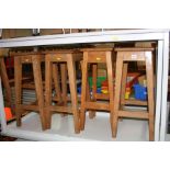 FOUR WOODEN STOOLS WITH RECTANGULAR TOPS, with hand hold cut away in centre of seat, heights 61.