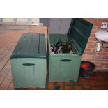 TWO GREEN PLASTIC GARDEN BOXES, one containing a quantity of Hockey sticks, bags from makers such as