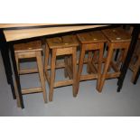 FOUR WOODEN STOOLS WITH RECTANGULAR TOPS, with hand hold cut away in the centre of the seat, heights