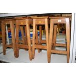 FOUR WOODEN STOOLS WITH RECTANGULAR TOPS, each with a hand hold to the centre of the seat, heights