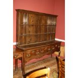 A GEORGIAN OAK DRESSER, with plate rack and three drawers, faced mahogany crossbanding, swan neck