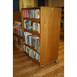 AN OAK VENEERED DOUBLE SIDED ROLLING BOOKCASE, with six adjustable shelves and wheels,