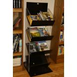 A BLACK AND CLEAR PERSPEX BOOK/MAGAZINE DISPLAY STAND, with four angled shelves, 48x45x143cm high