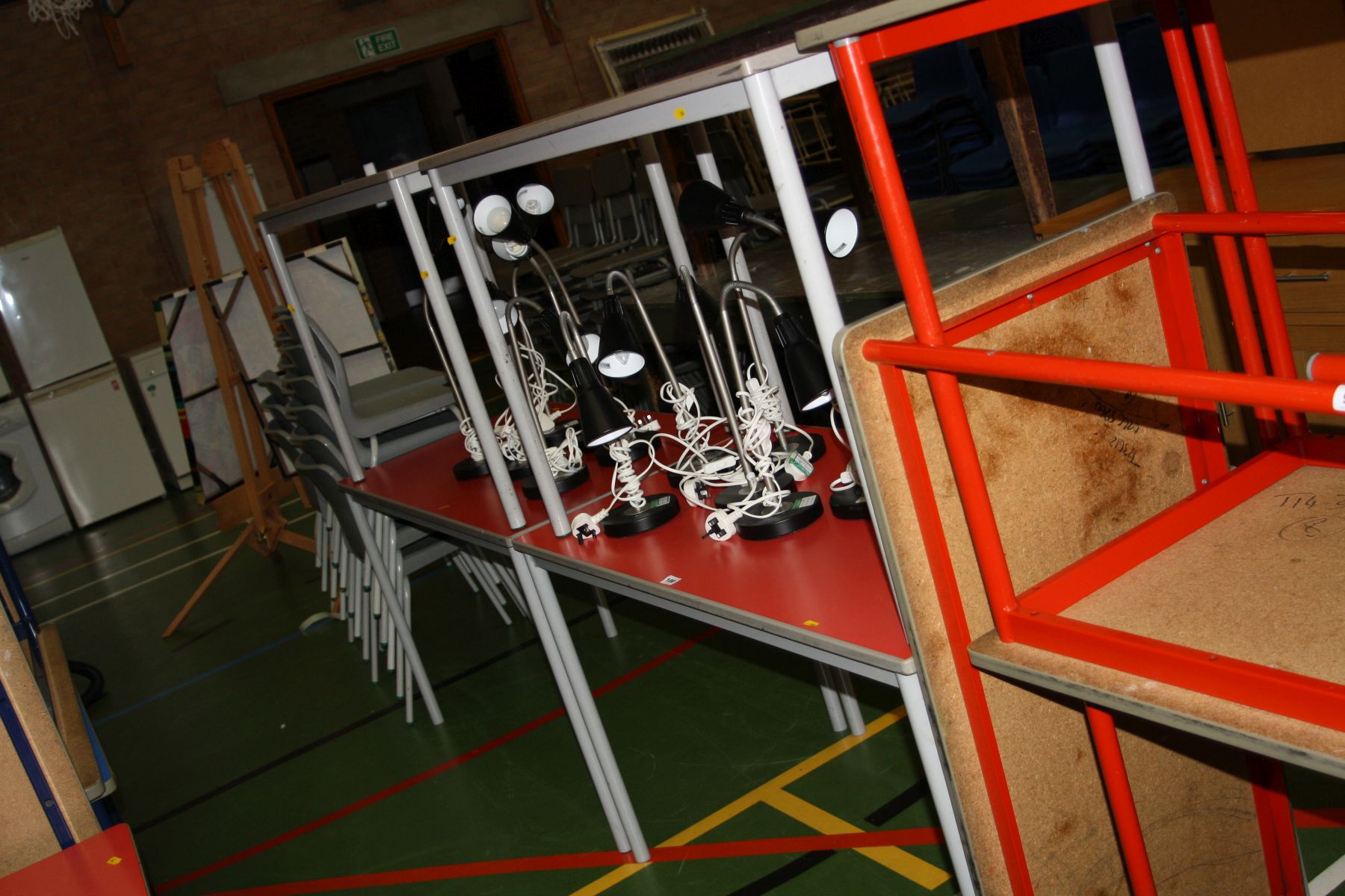 FOUR RED CLASSROOM TABLES, with a red melamine top, rubber edges and tubular metal legs