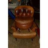 A BEIGE LEATHER SPOON BUTTON BACK ARMCHAIR ON MAHOGANY LEGS together with a matching pouffe (2)