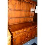 A REPRODUCTION CARVED OAK DRESSER with two tier plate rack and two drawers, width 129cm x depth 48cm