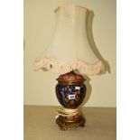 A CERAMIC LAMP BASE HAVING FLORAL AND FOLIATE DECORATION, incorporating a brass and pierced and