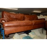 A TAN LEATHER TWO SEATER SETTEE ON MAHOGANY TURNED BUN FEET