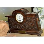 A CARVED OAK MANTLE CLOCK, Roman numerals, key present, having brass presentation plaque to front