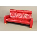 AN EKORNES STRESSLESS ARION RED LEATHER RECLINING THREE SEATER SETTEE, with adjustable head rests,