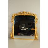 A MID VICTORIAN GILT GESSO FRAMED OVERMANTEL MIRROR, the surmount of foliate scrolls, flower heads