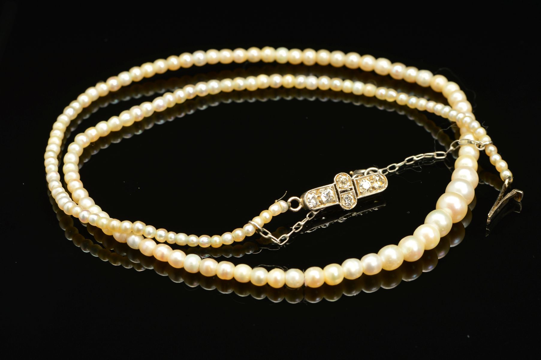 AN EARLY 20TH CENTURY NATURAL SALTWATER PEARL GRADUATED SINGLE ROW PEARL NECKLACE, accompanied by