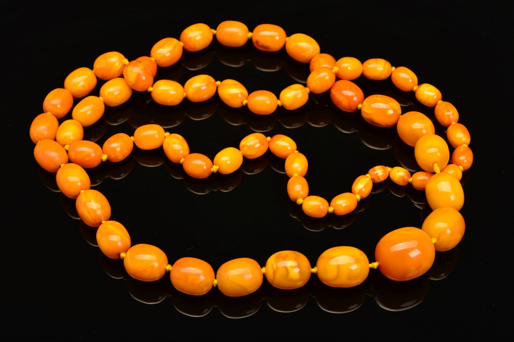 A LONG NATURAL AMBER BEAD NECKLACE, designed as sixty one graduated barrel shape butterscotch