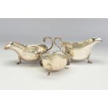 THREE GEORGE V SILVER SAUCE BOATS, comprising one with foliate cast handle, crimped rim, shell