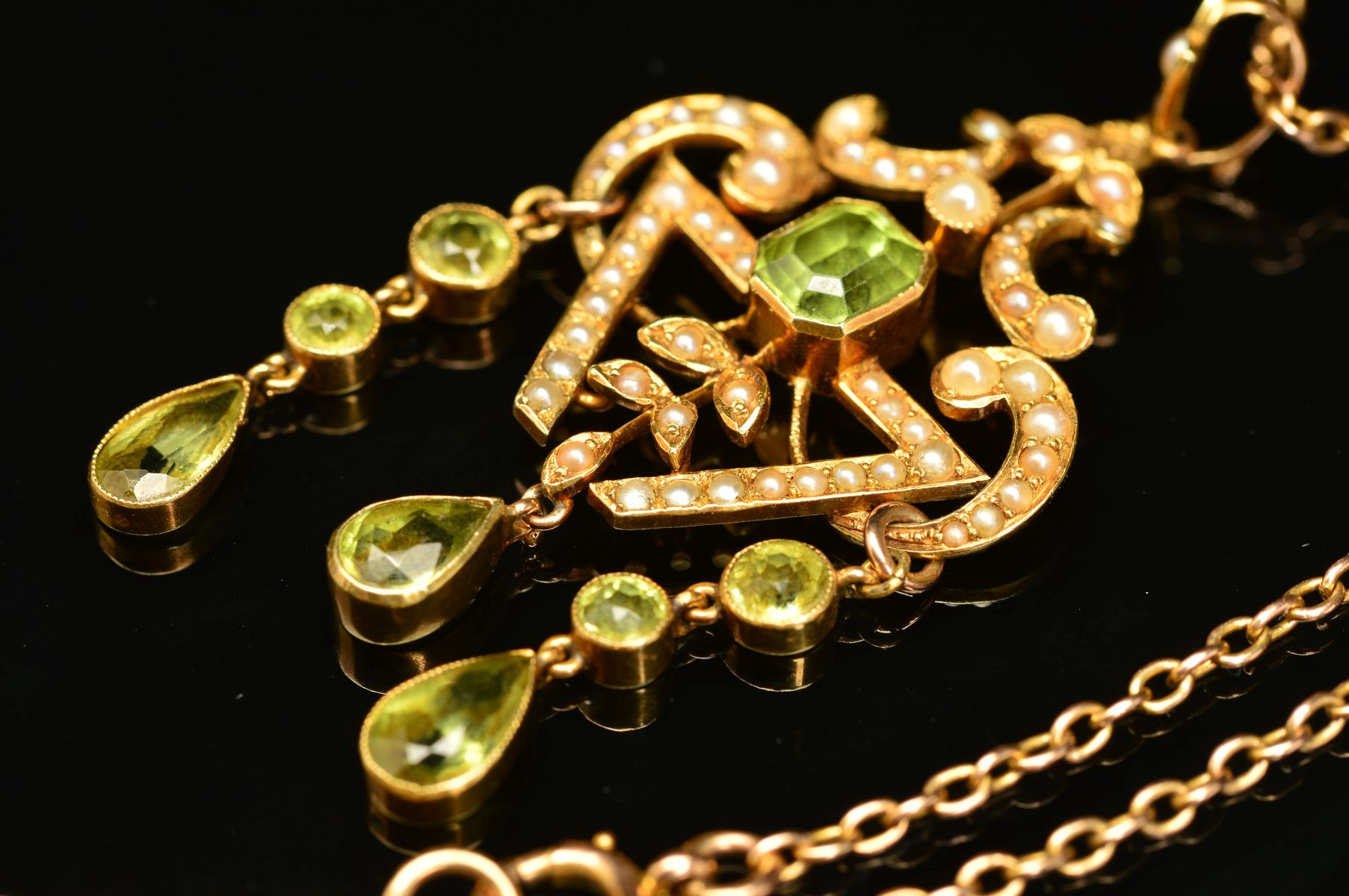 AN EARLY 20TH CENTURY PERIDOT AND SEED PEARL PENDANT, a fancy open scroll work design, suspending - Image 2 of 4