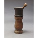 A large cast iron mortar, probably 18th century, 28cm high, together with a turned wood pestle and a