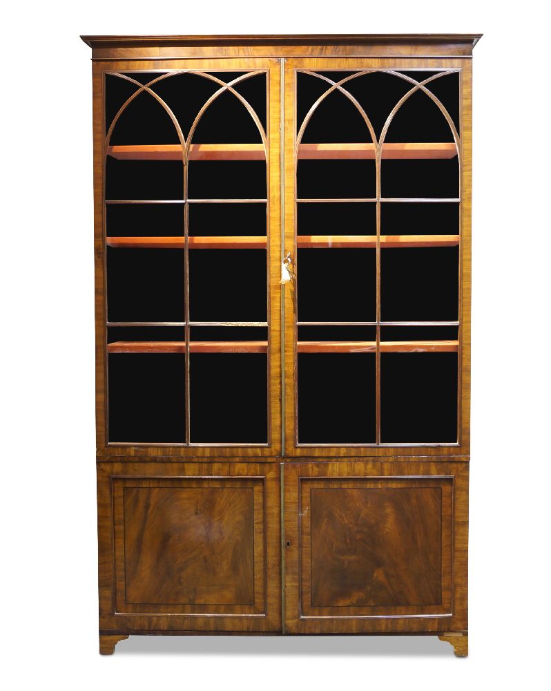 A George III mahogany and crossbanded bookcase, the moulded cornice above two Gothic arch astragal