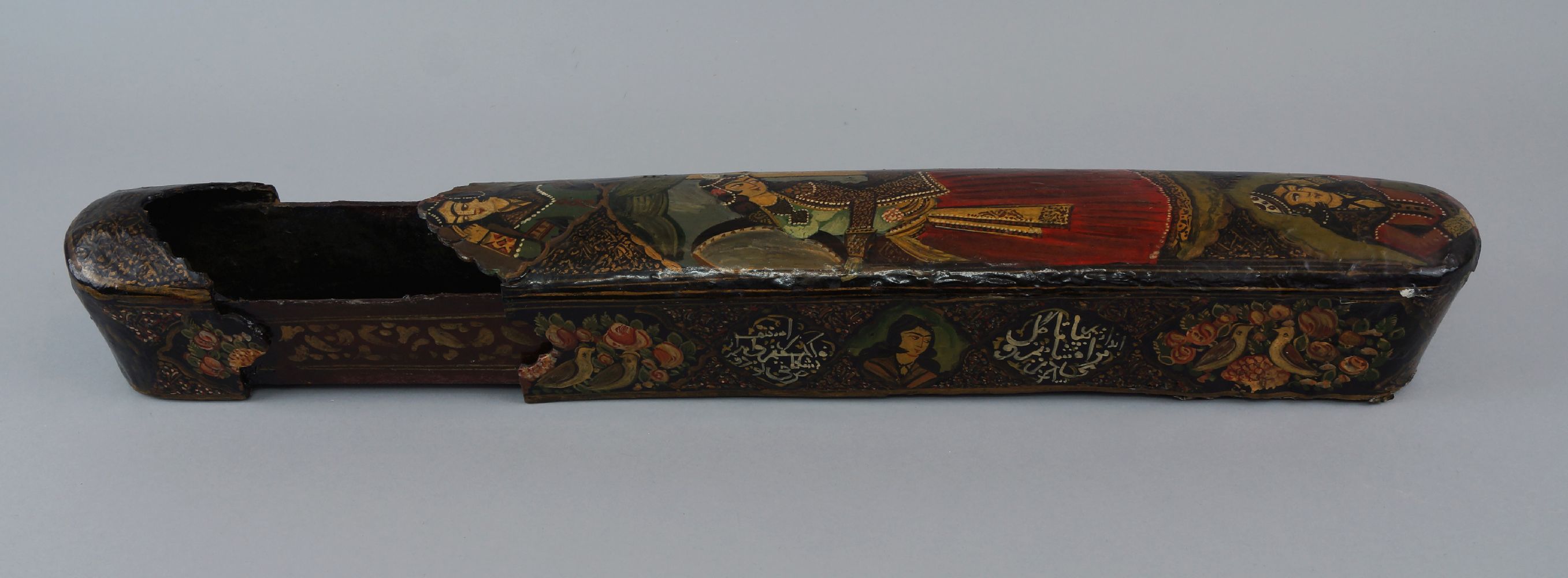 A large papier mache and lacquered qalamdan/ pen box,19th century, decorated to the sliding lid with