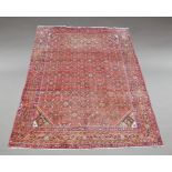 A large Hamadan woolen carpet, the central reserve decorated with geometric motifs on a red ground