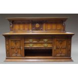 A large Edwardian carved oak sideboard, the raised paneled back centered by carved vacant cartouche,