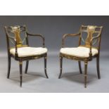 A pair of Regency style ebonised, painted and caned open armchairs, late 19th, early 20th Century,