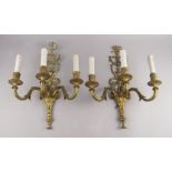 A set of seven gilt metal three light wall appliques, in the Adam taste, with scrolling back