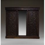 A carved oak and mirrored triple wardrobe, early 20th Century, with overall carved foliate